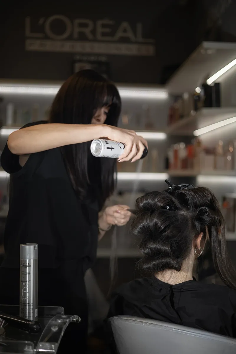 A Jarka Čechová salon stylist setting a client’s hairstyle with hairspray