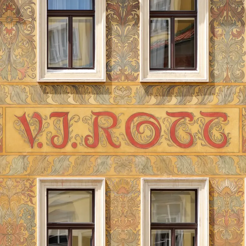 The painted facade of the V.J. Rott building in Prague with wooden windows